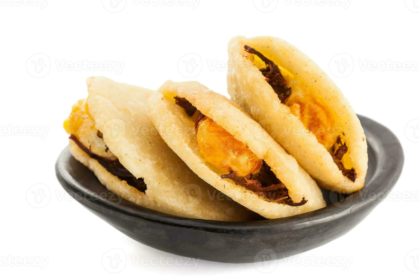 arepa de huevo. tradizionale colombiano fritte arepa pieno con uovo e triturati carne servito nel un' nero ceramica piatto su bianca sfondo foto