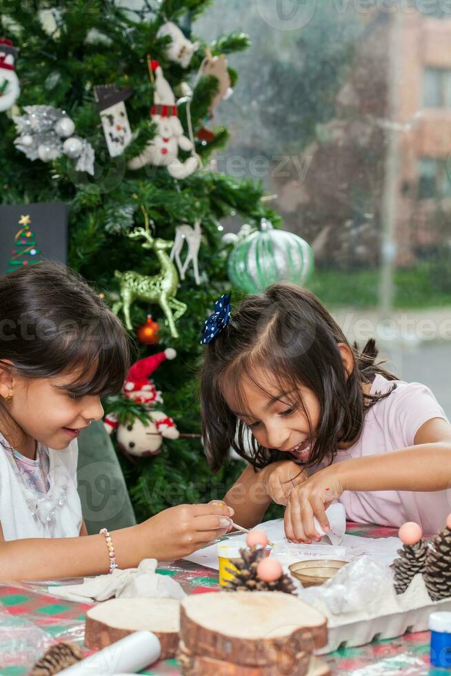 Due poco sorelle avendo divertimento mentre fabbricazione Natale Natività mestieri con a casa - vero famiglia foto