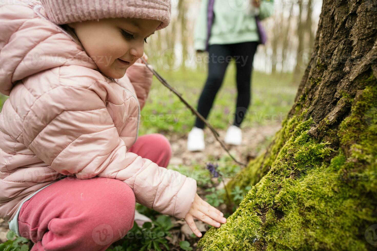 un' poco ricercatore di il foresta. il ragazza tocchi muschio su il albero. foto