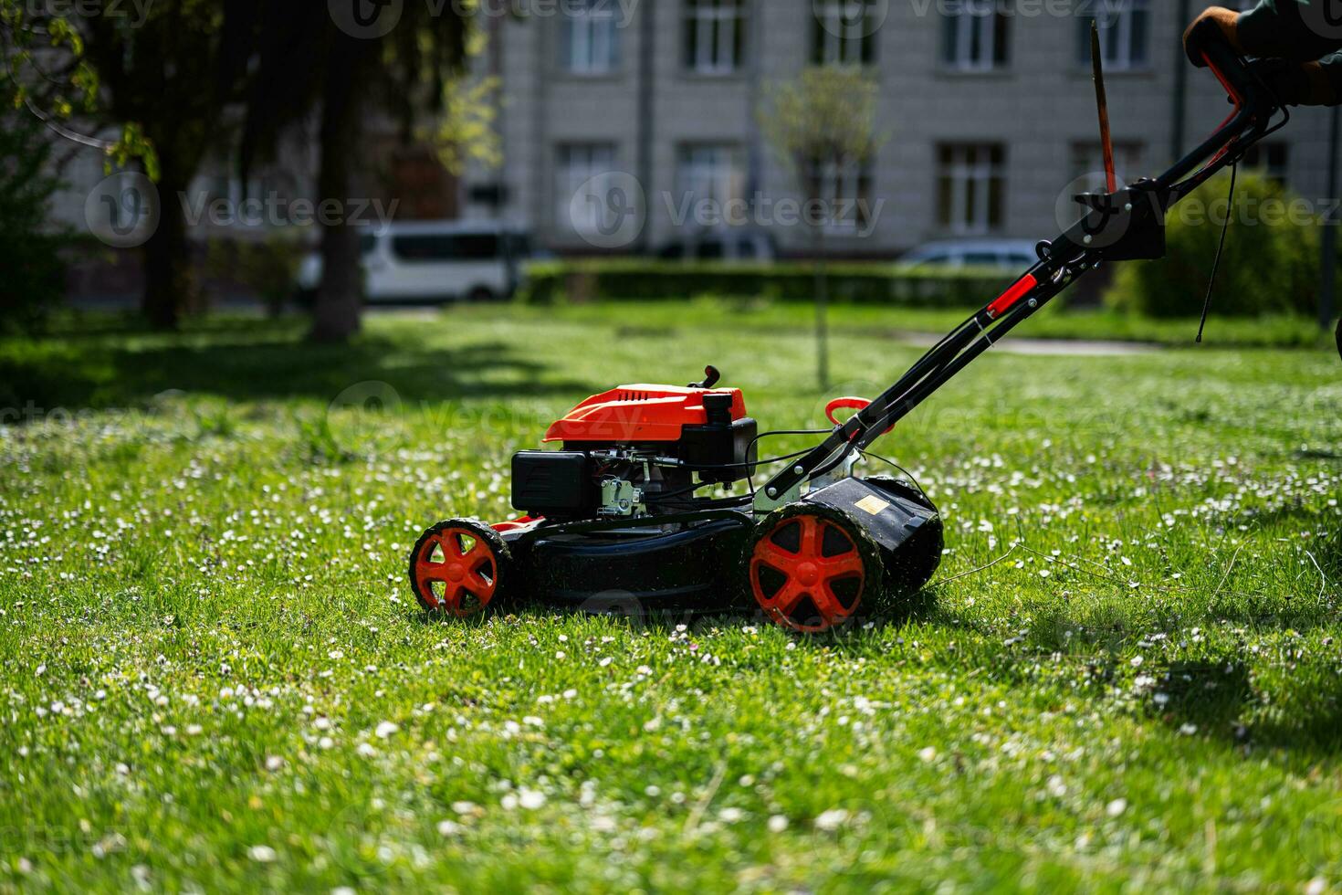 comunale Servizi giardiniere lavoratore uomo utilizzando prato falciatore per erba taglio nel città parco. foto