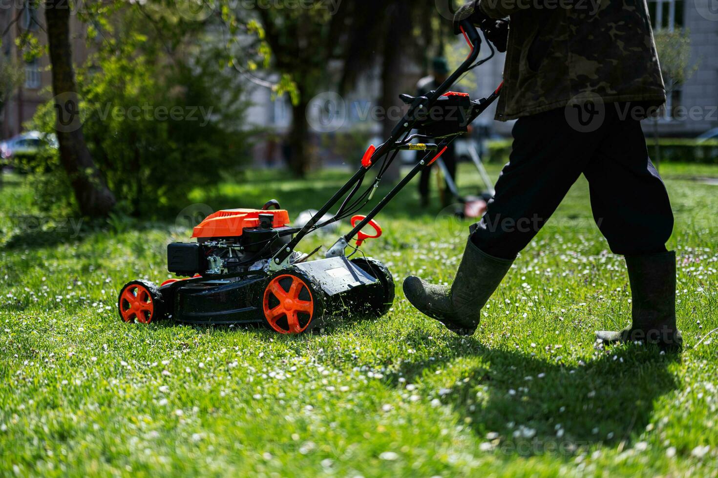 comunale Servizi giardiniere lavoratore uomo utilizzando prato falciatore per erba taglio nel città parco. foto