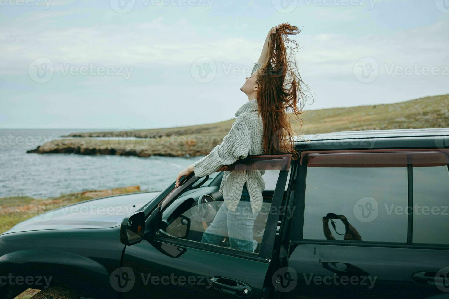 donna con rosso capelli nel un' maglione vicino il auto natura femmina rilassante foto