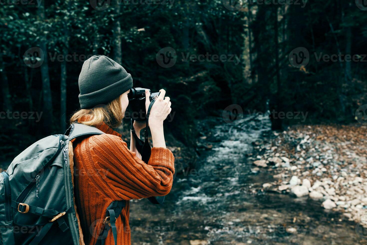 donna con un' telecamera su natura nel il montagne vicino il fiume lato Visualizza foto
