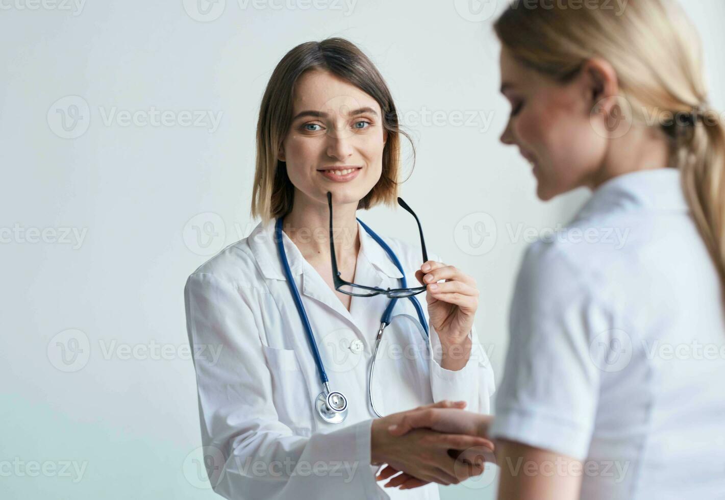 bellissimo donna medico con stetoscopio tremante mani con femmina paziente foto