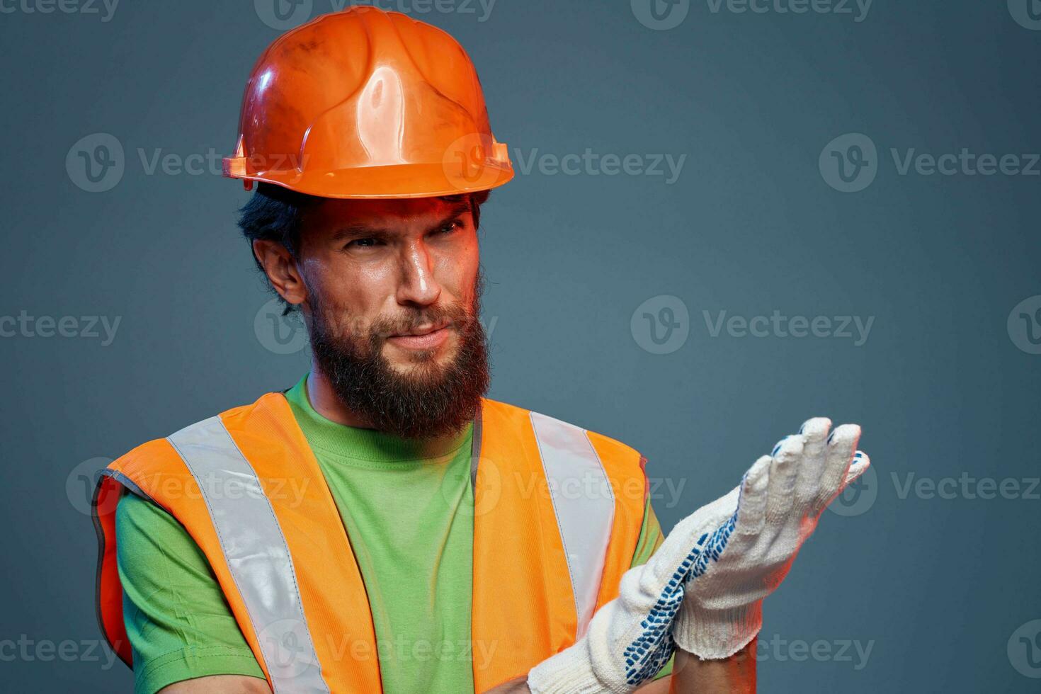 barbuto uomo nel arancia difficile cappello guanti professionale ritagliata Visualizza blu sfondo foto