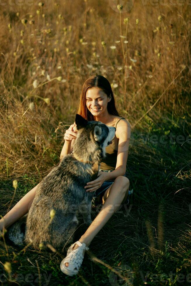 donna seduta nel un' campo con un' bassotto cane sorridente mentre la spesa tempo nel natura con un' amico cane nel autunno a tramonto foto