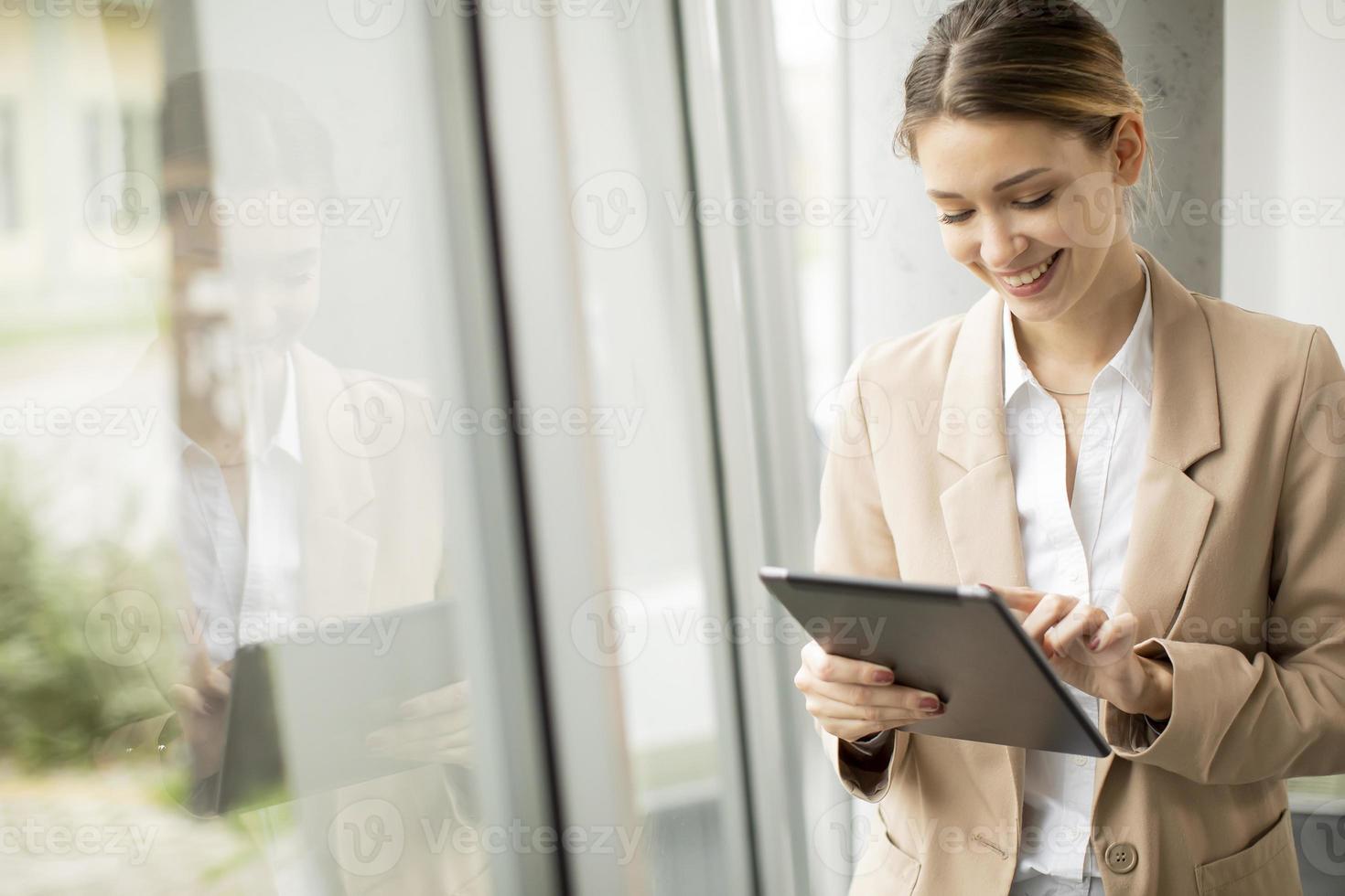 giovane donna che tiene tavoletta digitale in ufficio moderno foto