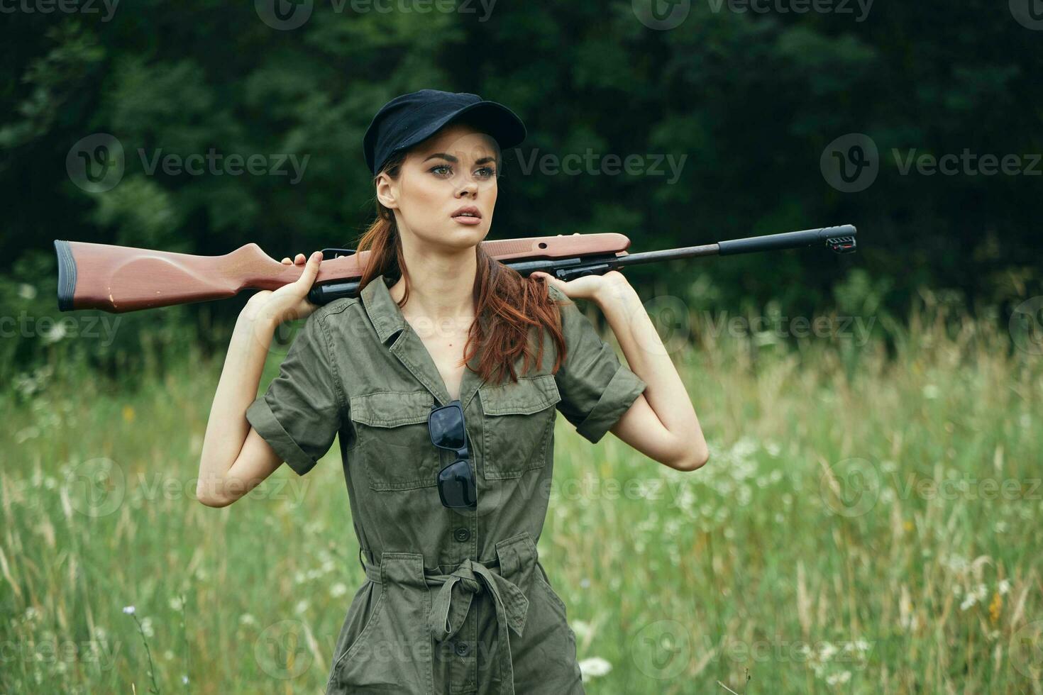 militare donna Tenere un' arma dietro a il suo indietro nero berretto a caccia stile di vita verde tuta da lavoro foto