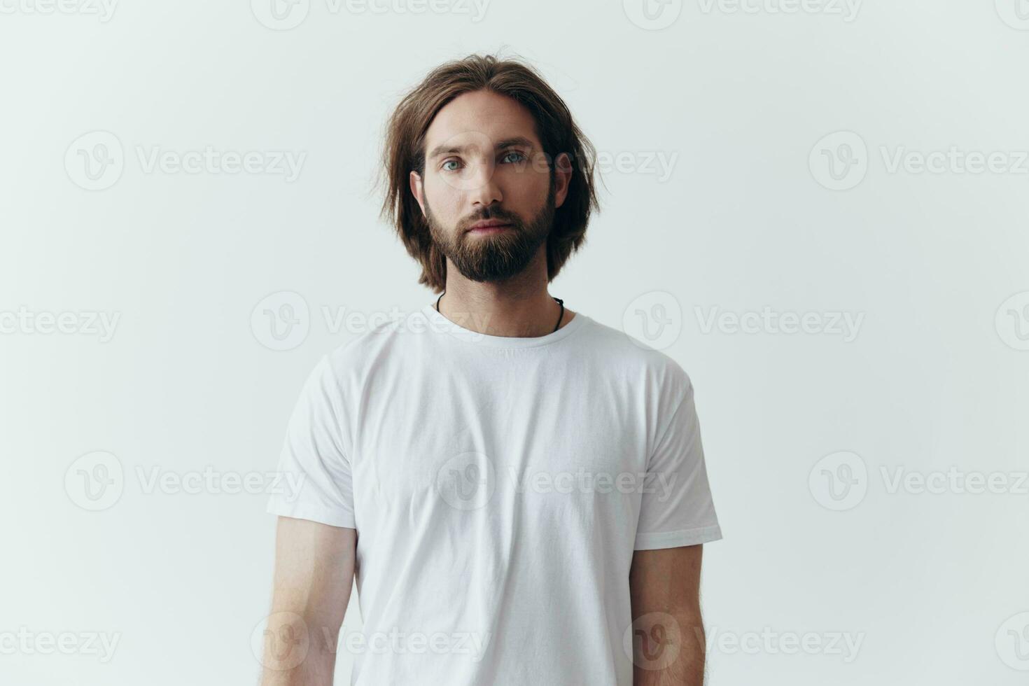 ritratto di un' uomo con un' nero di spessore barba e lungo capelli nel un' bianca maglietta su un' bianca isolato sfondo stile di vita senza pathos ogni giorno Immagine foto