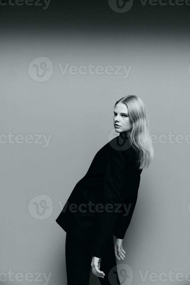 il bellezza Leans Indietro, abbassamento sua mani fuori uso. un' elegante signora nel un' completo da uomo pose con volante capelli nel il studio. il concetto di stile per Marche foto