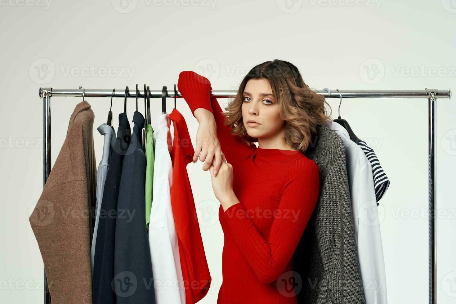 bella donna nel un' rosso giacca vicino il armadio leggero sfondo foto