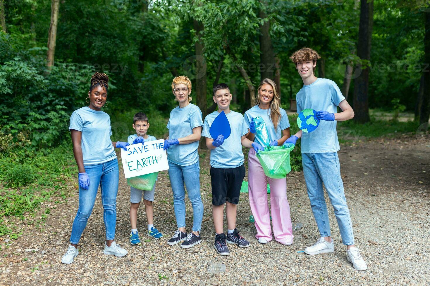 diverso gruppo di persone raccolta su spazzatura nel il parco volontario Comunità servizio. contento internazionale volontari Tenere cartellone con 'salva il terra' Messaggio. foto