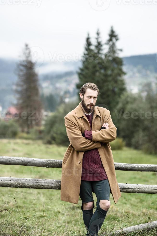 uomo con un cappotto marrone e pantaloni strappati foto