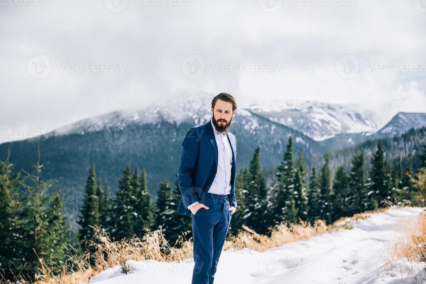 sposo in abito blu nelle montagne dei carpazi foto