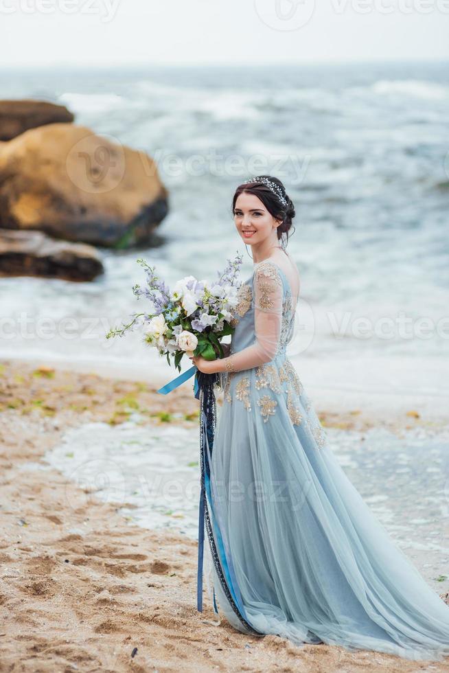 sposa con un mazzo di fiori sulla spiaggia foto