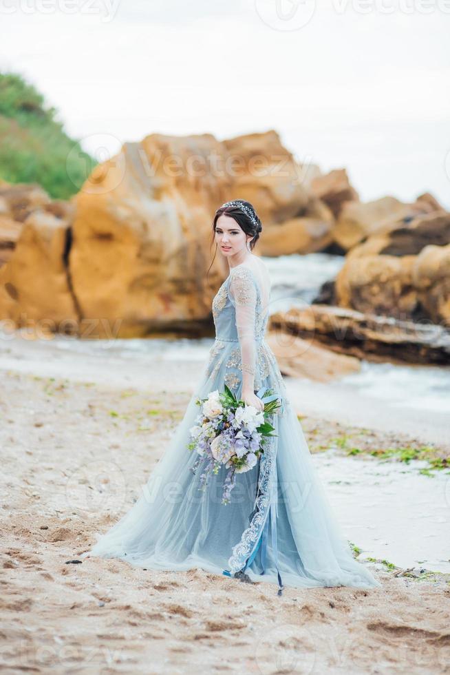 sposa con un mazzo di fiori sulla spiaggia foto