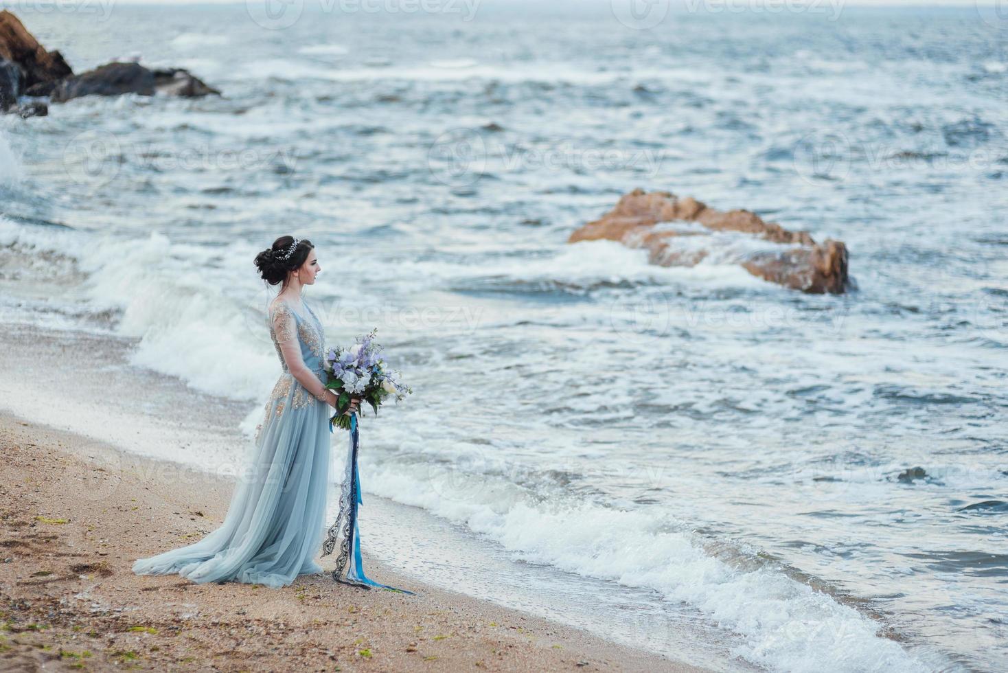 sposa con un mazzo di fiori sulla spiaggia foto