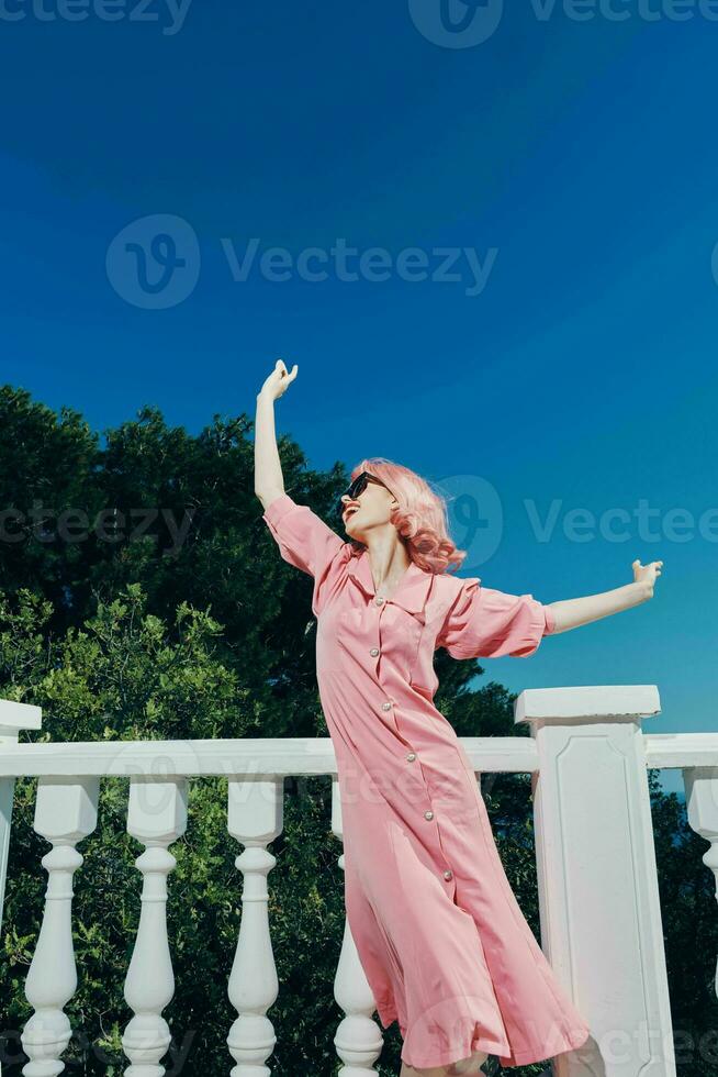 attraente donna con rosa capelli indossare occhiali da sole in posa rilassamento concetto foto
