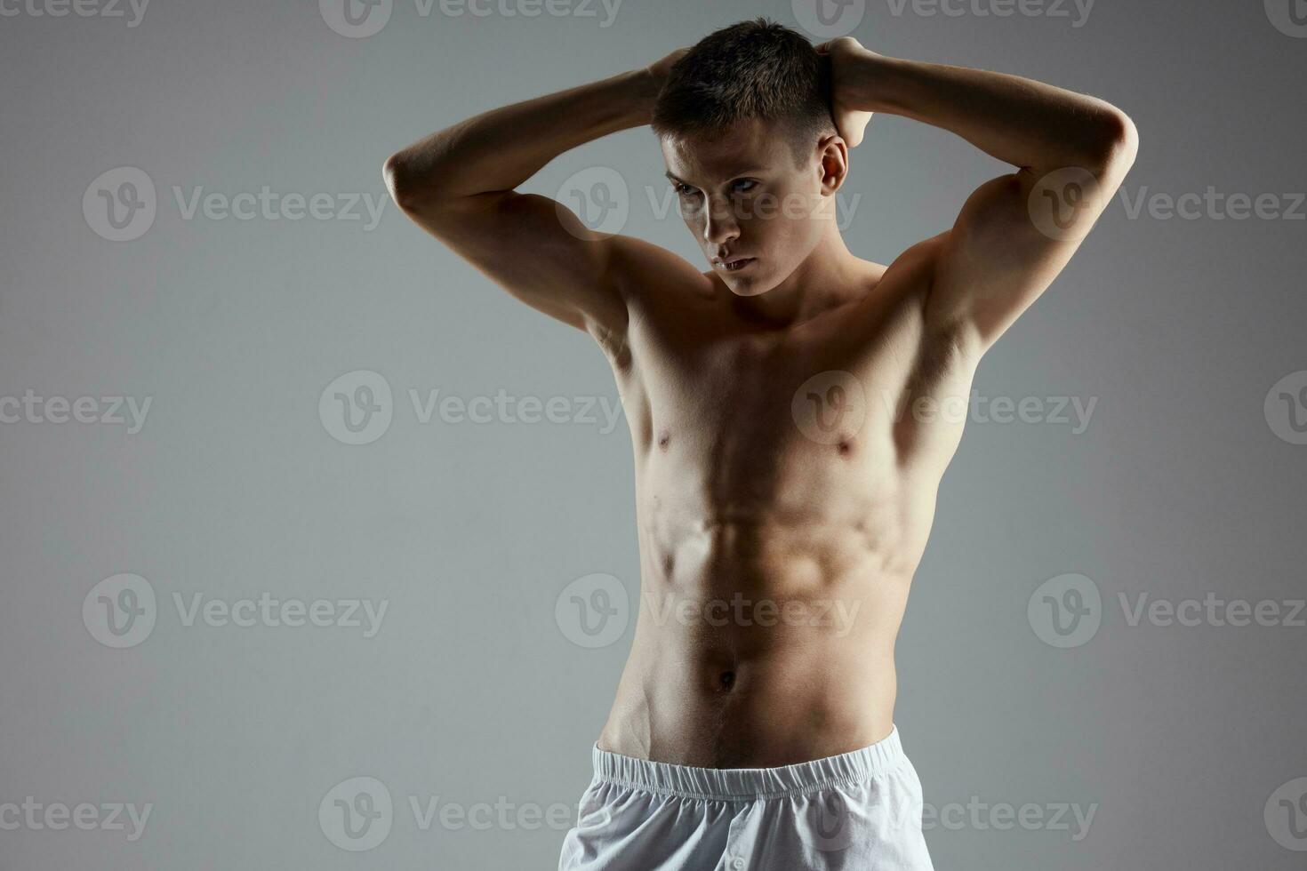 uomo con pompato su braccio muscoli su un' grigio sfondo e addominali cubi su il suo stomaco foto