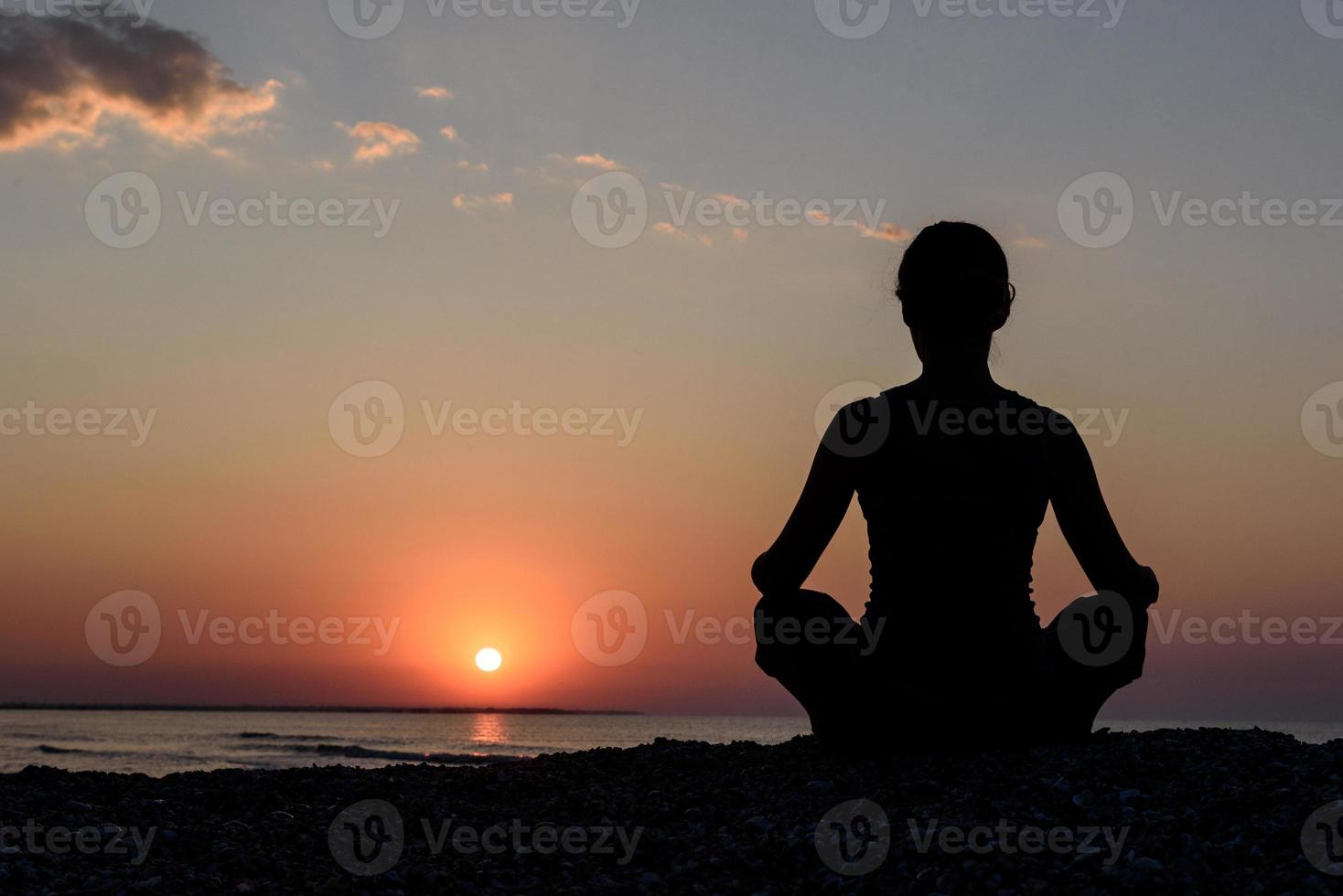 ragazza sulla spiaggia all'alba nello yoga assana foto