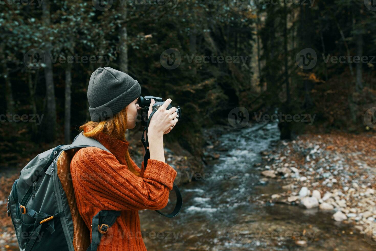 donna fotografo Tenere un' telecamera nel mano vicino il fiume nel il montagne e foresta nel il sfondo foto