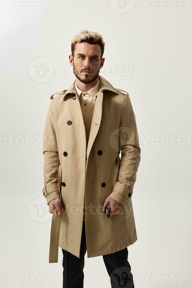 elegante giovane uomo nel beige cappotto e pantaloni ritagliata Visualizza maglione modello foto