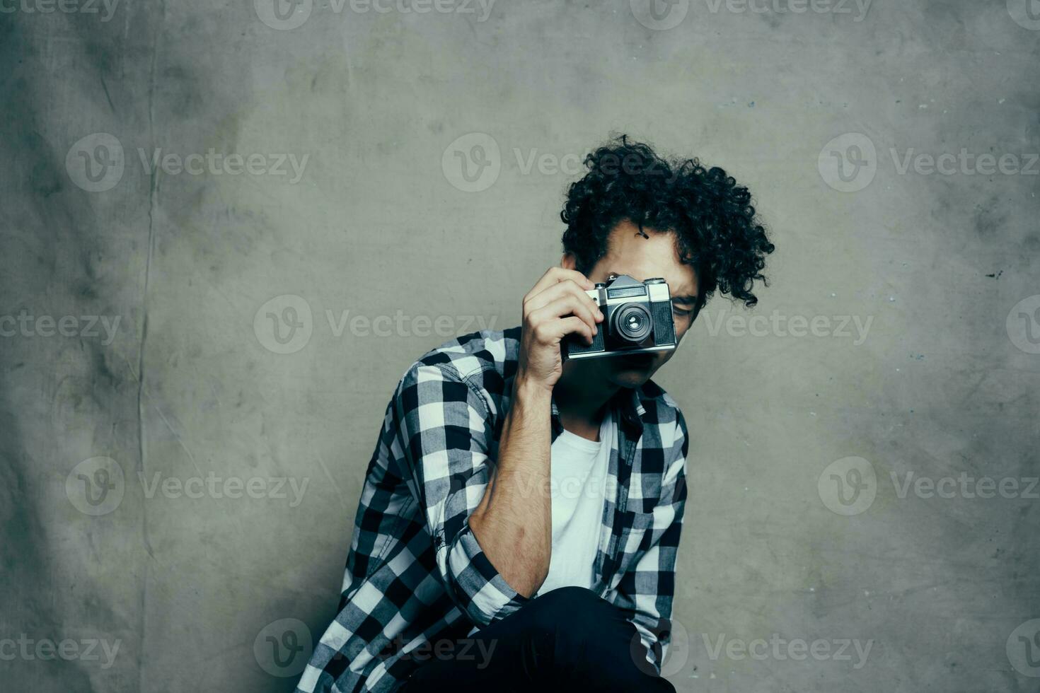 bello maschio modello nel un' camicia e un' maglietta su un' grigio sfondo Riccio capelli acconciatura telecamera studio foto