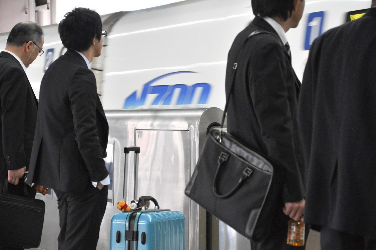 Tokyo, Giappone, 4 novembre 2014 - un gruppo di uomini d'affari in piedi sulla piattaforma di una stazione dei treni ad alta velocità e in attesa dell'orario di partenza durante le ore di punta foto