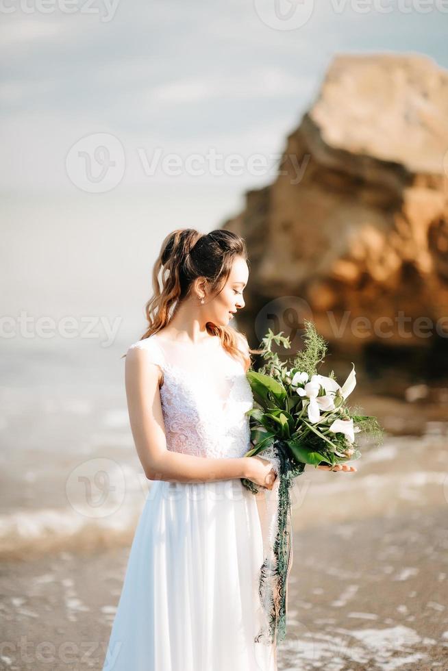 sposa con un bouquet da sposa in riva al mare foto