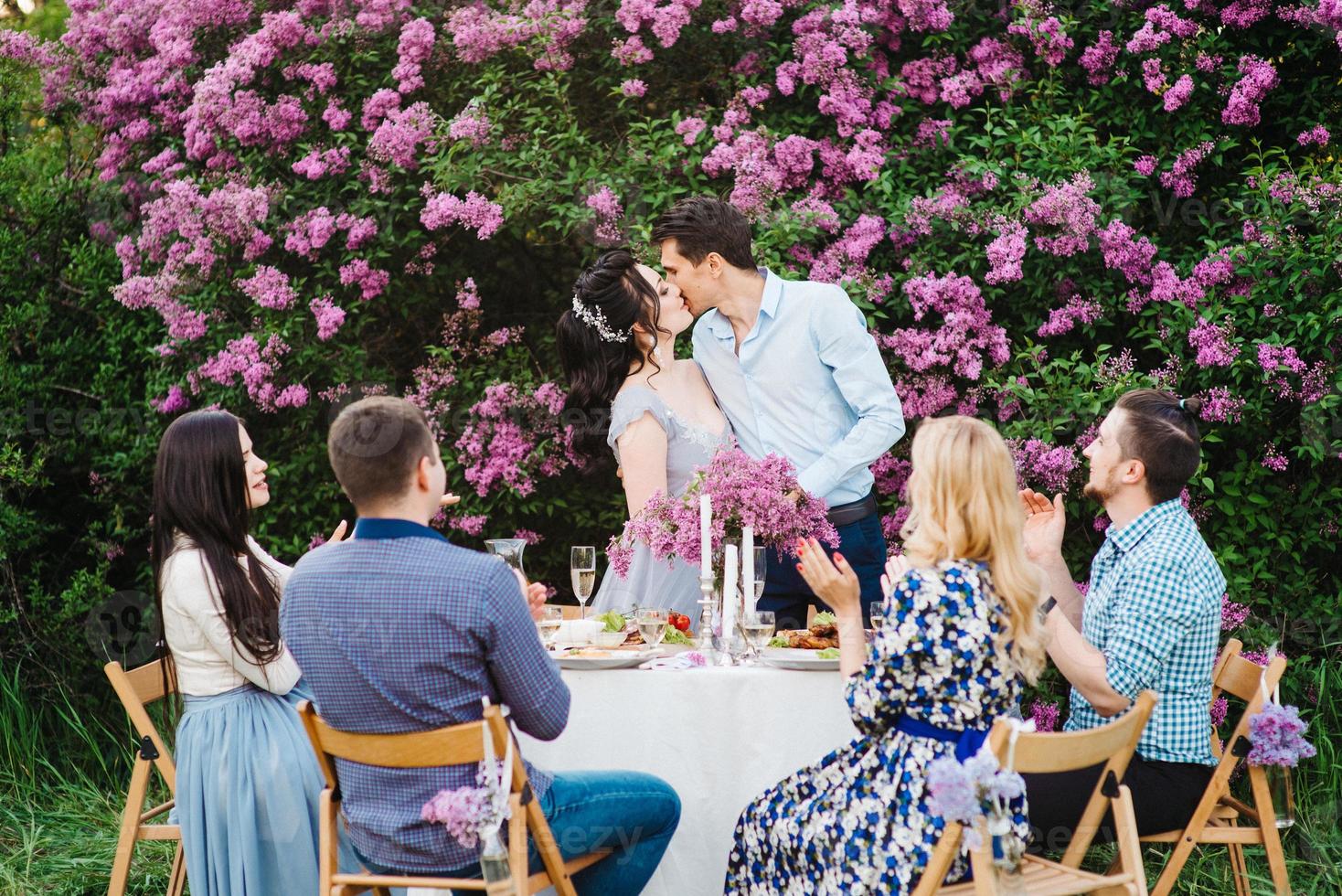 sposa e sposo a un tavolo di nozze con gli amici foto