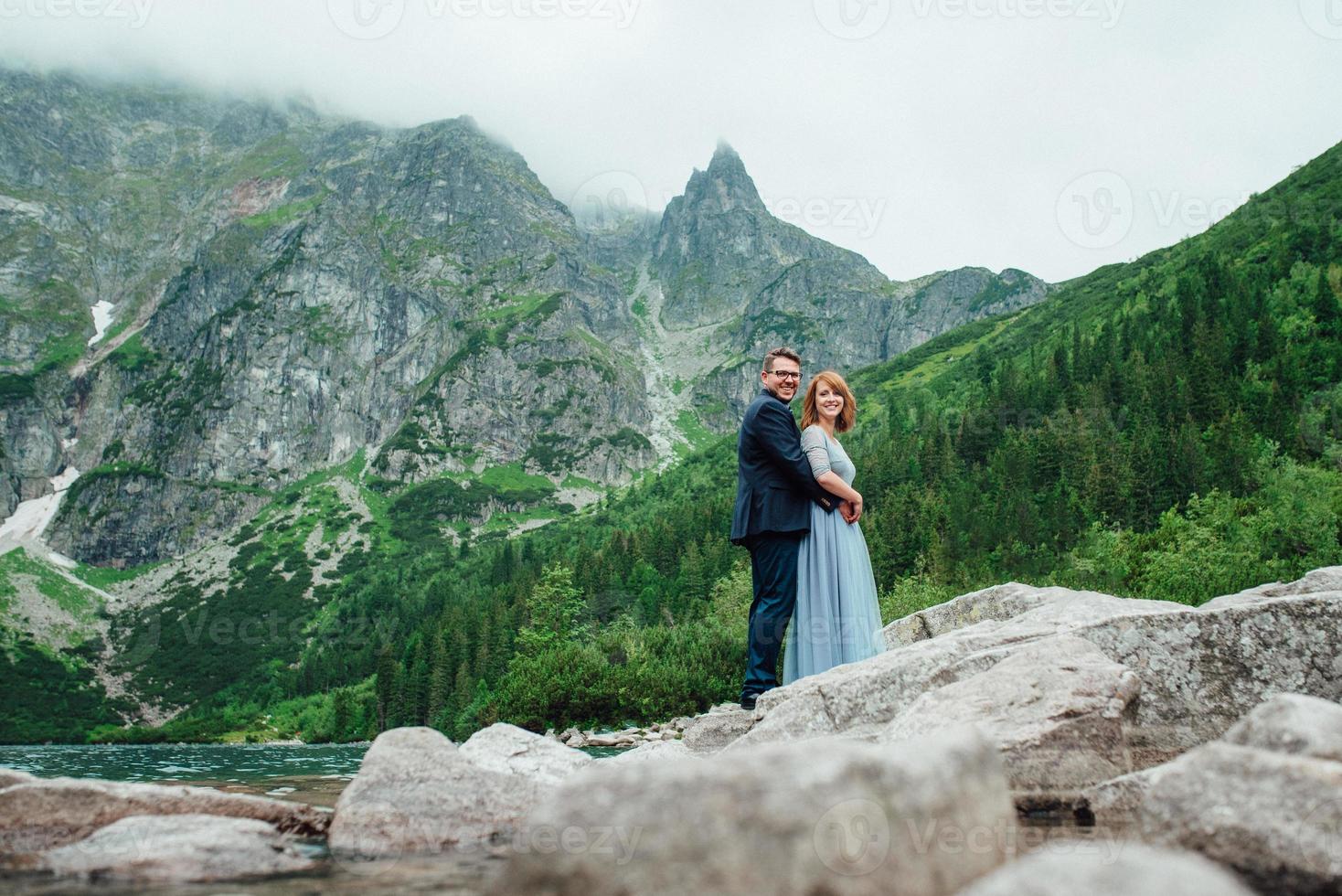 giovane coppia in una passeggiata vicino al lago circondato dalle montagne foto