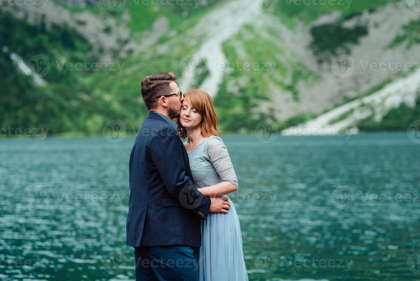 giovane coppia in una passeggiata vicino al lago circondato dalle montagne foto