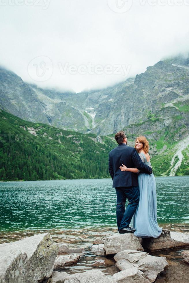 giovane coppia in una passeggiata vicino al lago circondato dalle montagne foto