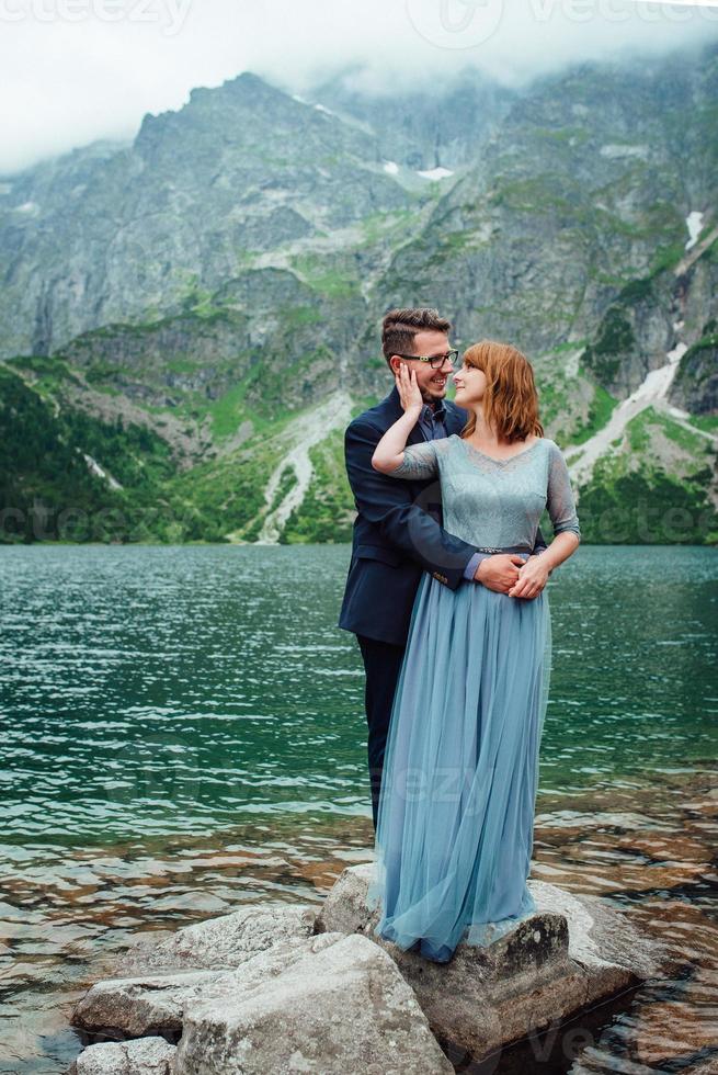 giovane coppia in una passeggiata vicino al lago circondato dalle montagne foto