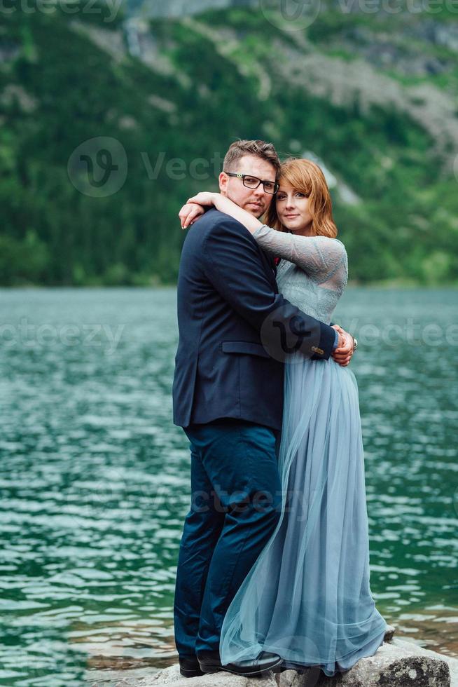 giovane coppia in una passeggiata vicino al lago circondato dalle montagne foto