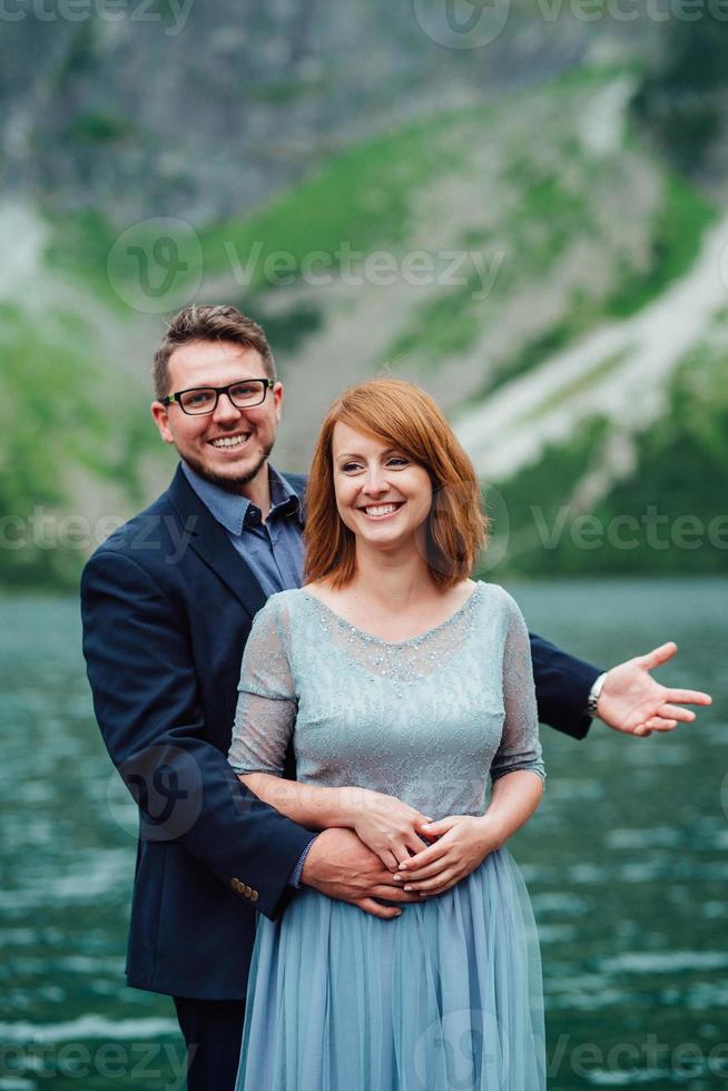 giovane coppia in una passeggiata vicino al lago circondato dalle montagne foto