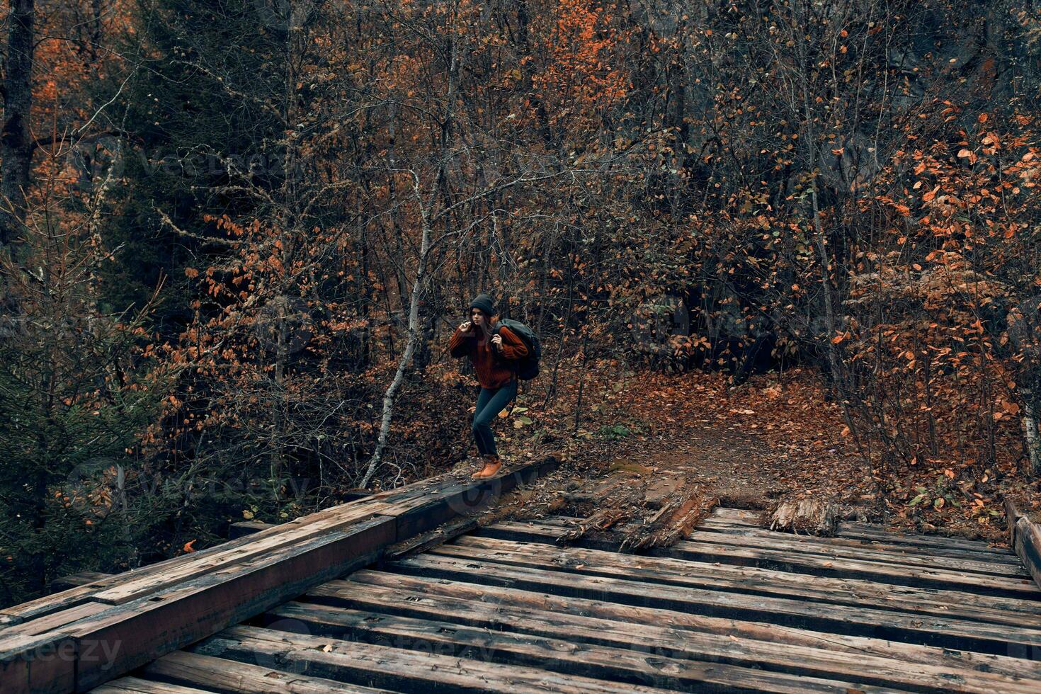 donna turista croci il ponte al di sopra di il fiume viaggio nel autunno foto