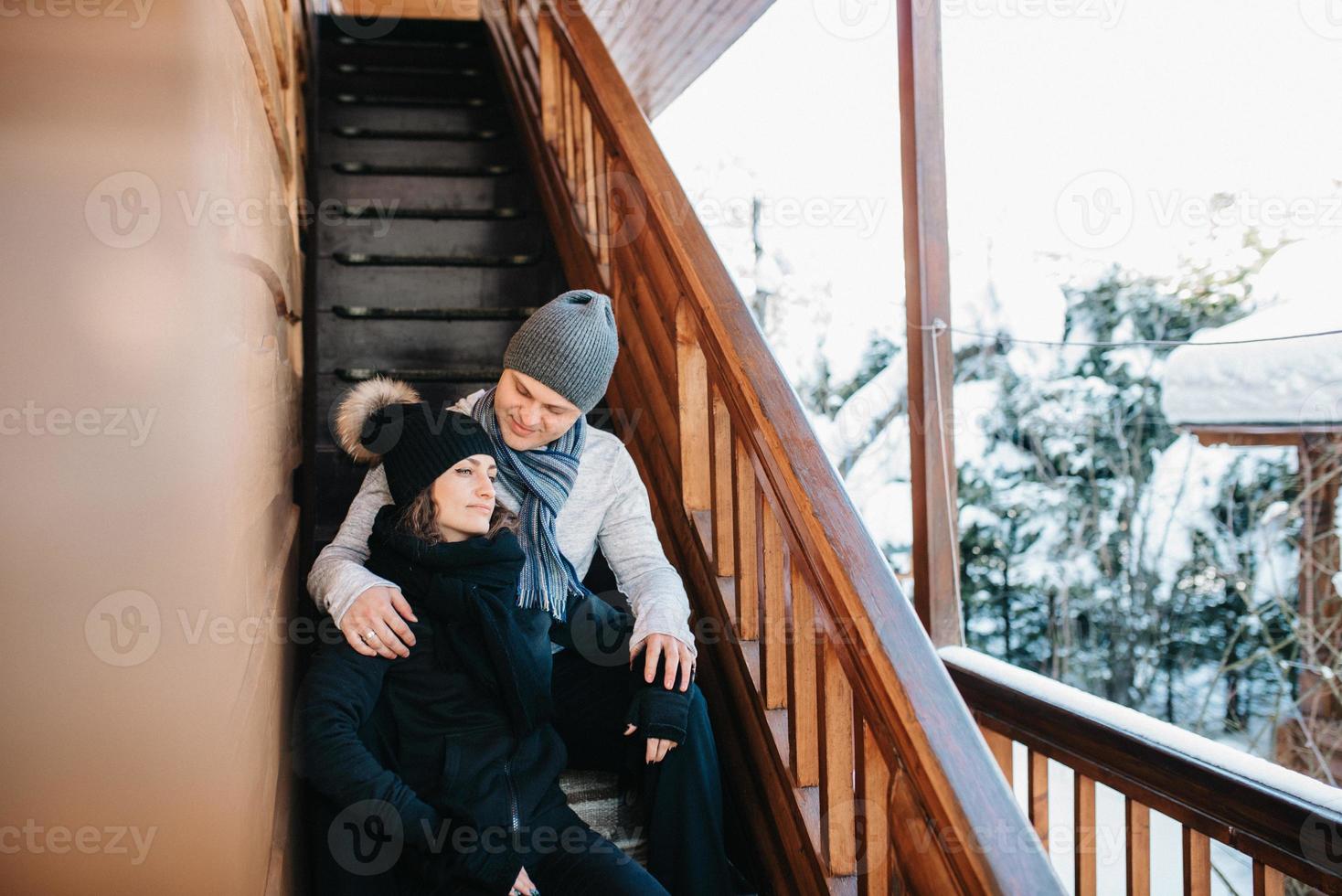 coppia di giovani un ragazzo e una ragazza sotto il portico di una casa in legno coperta di neve foto