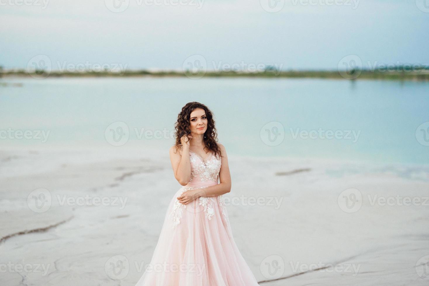 ragazza in un vestito rosa sta camminando lungo la sabbia bianca foto