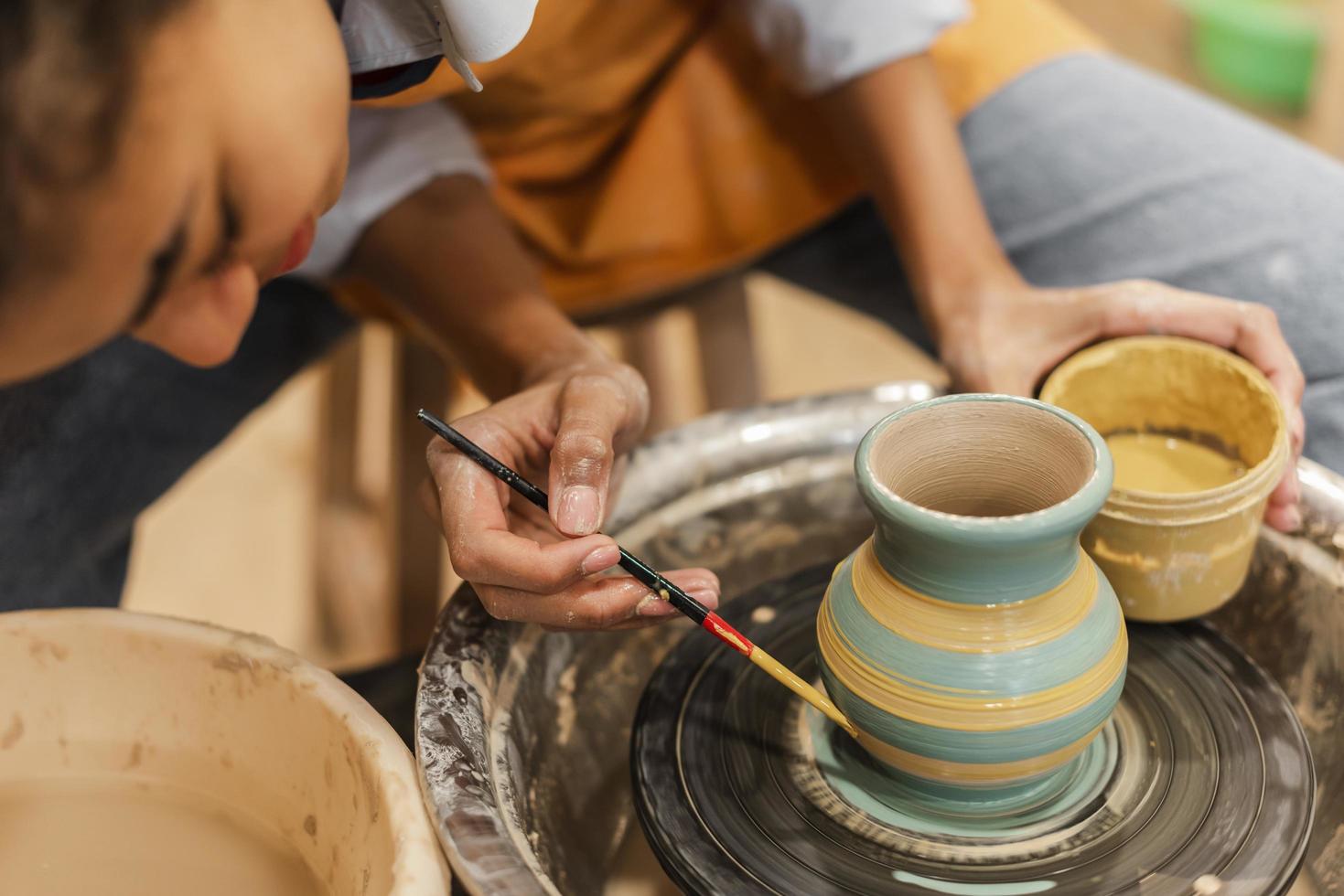 mani con pennello e pentola di terracotta foto