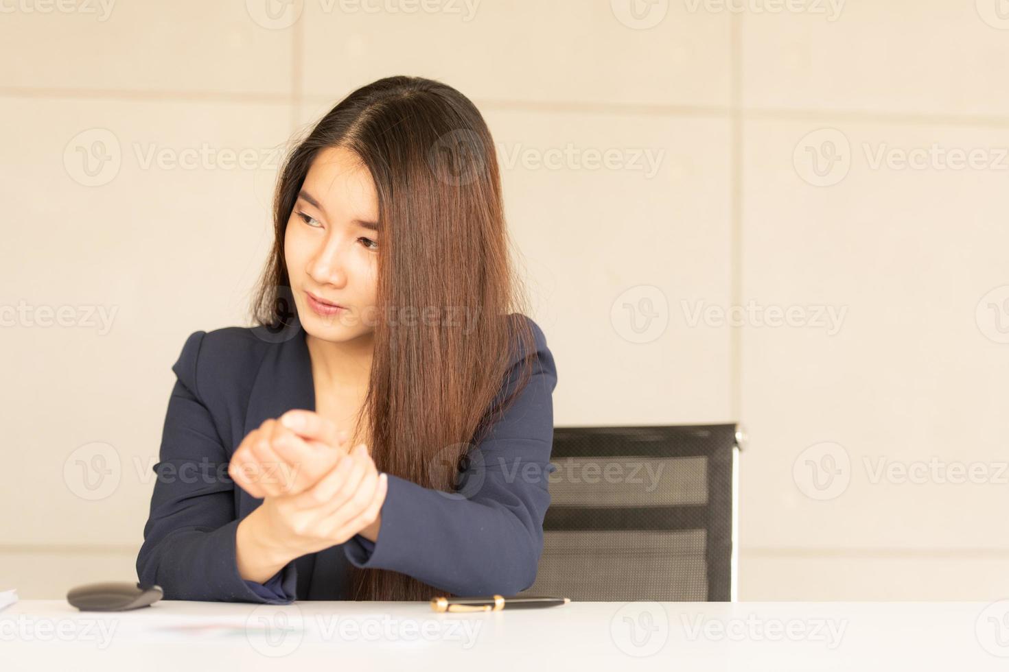 donna asiatica di affari che tiene il suo dolore al polso dal lavoro e dall'utilizzo del computer. sindrome dell'ufficio foto
