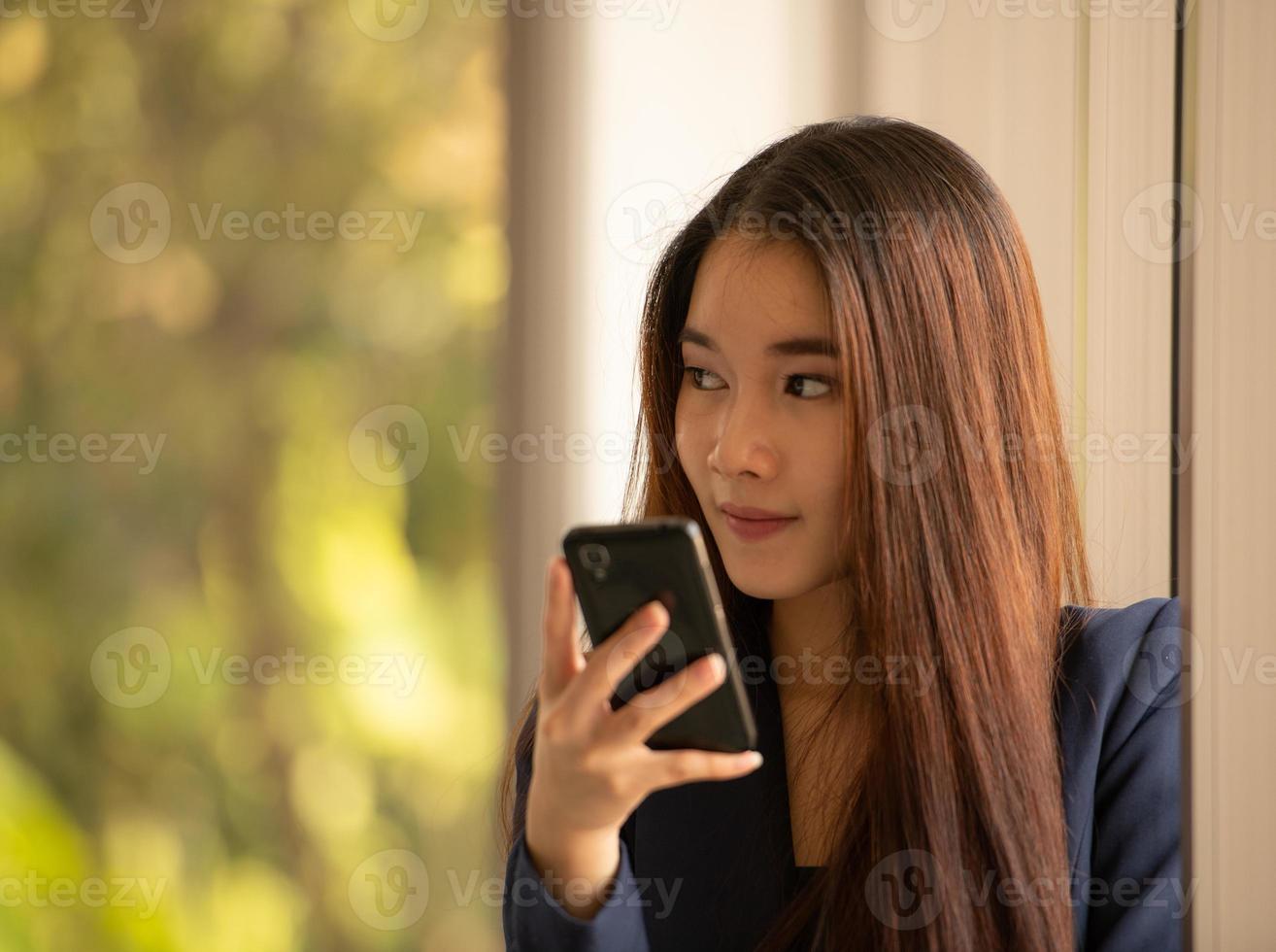 donna asiatica di affari che per mezzo del telefono cellulare in un ufficio foto