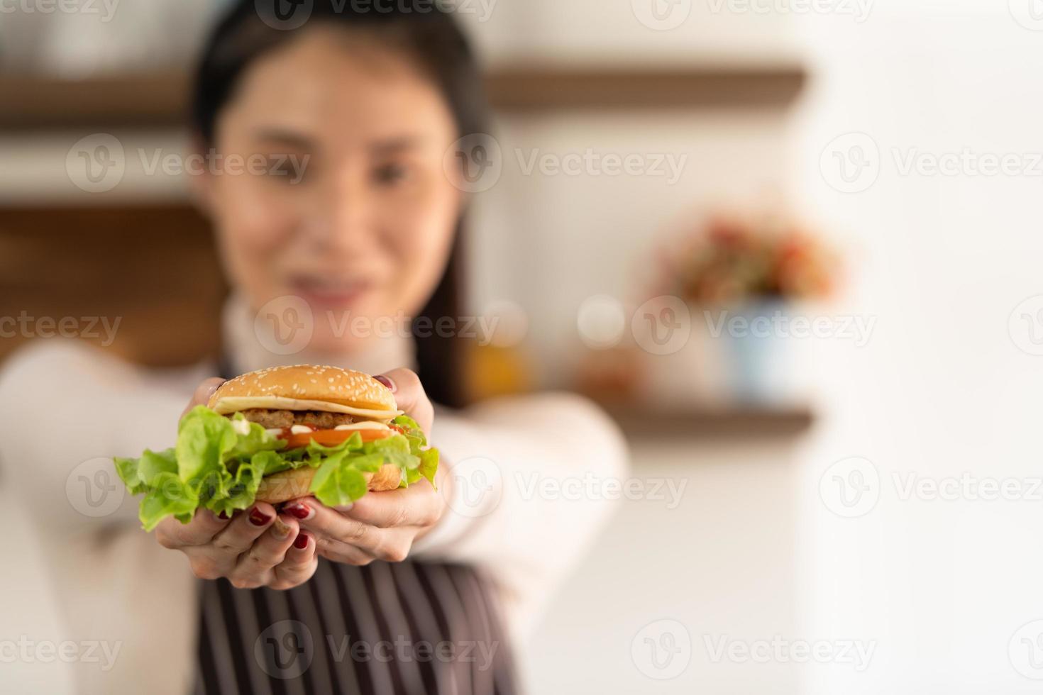 un hamburger che cucina da giovane donna in cucina con un sorriso e felicità foto