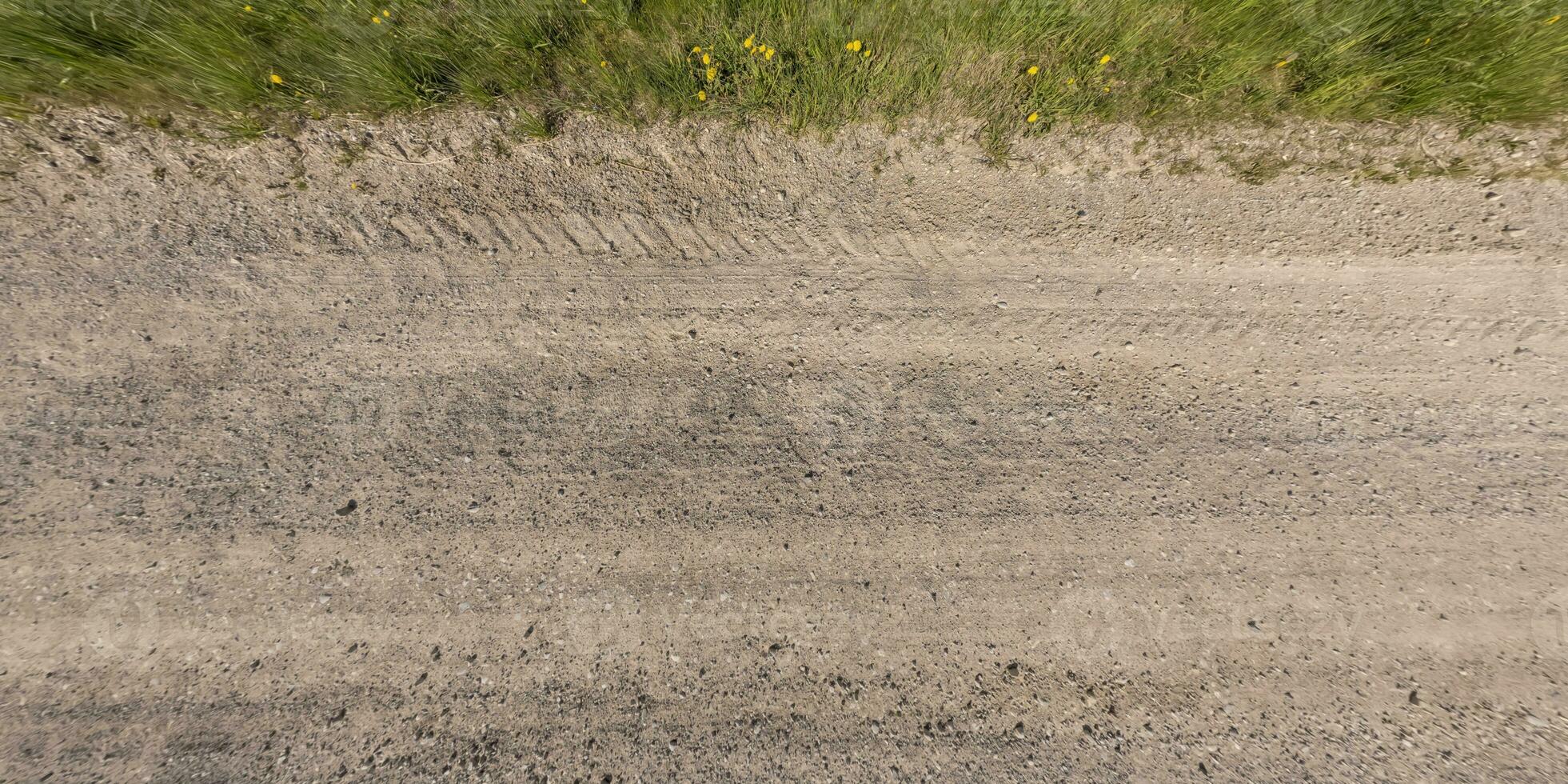 panorama di superficie a partire dal sopra di ghiaia strada con auto pneumatico brani con ciglio della strada e erba foto