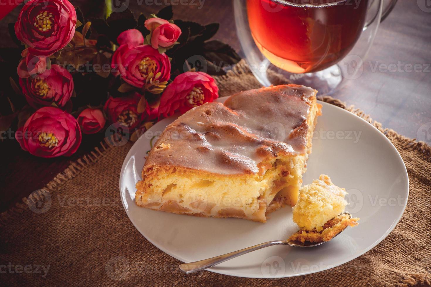 un pezzo di torta di mele su un piatto bianco su uno sfondo di fiori rosa foto