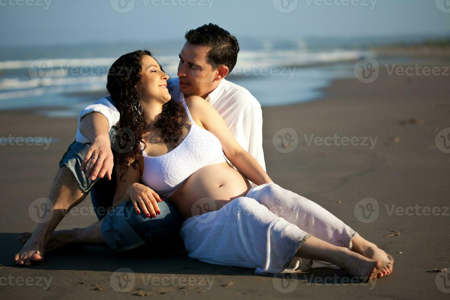 coppia a il spiaggia in attesa per loro bambino - 28 settimane foto