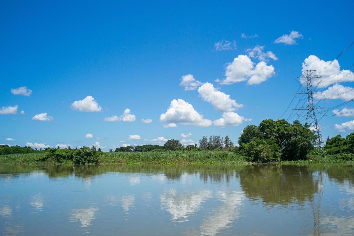 paesaggio di fiume e cielo azzurro con nuvole. torre ad alta tensione e linee di cavi elettrici attraverso il fiume con un cielo blu sullo sfondo. foto