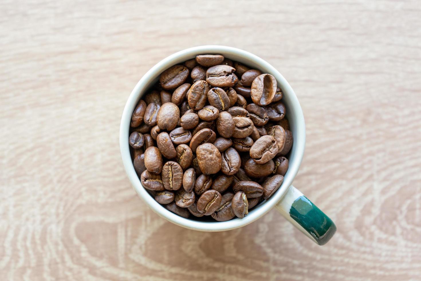 vista ingrandita di molti chicchi di caffè in una tazza di ceramica con copia spazio per aggiungere del testo foto