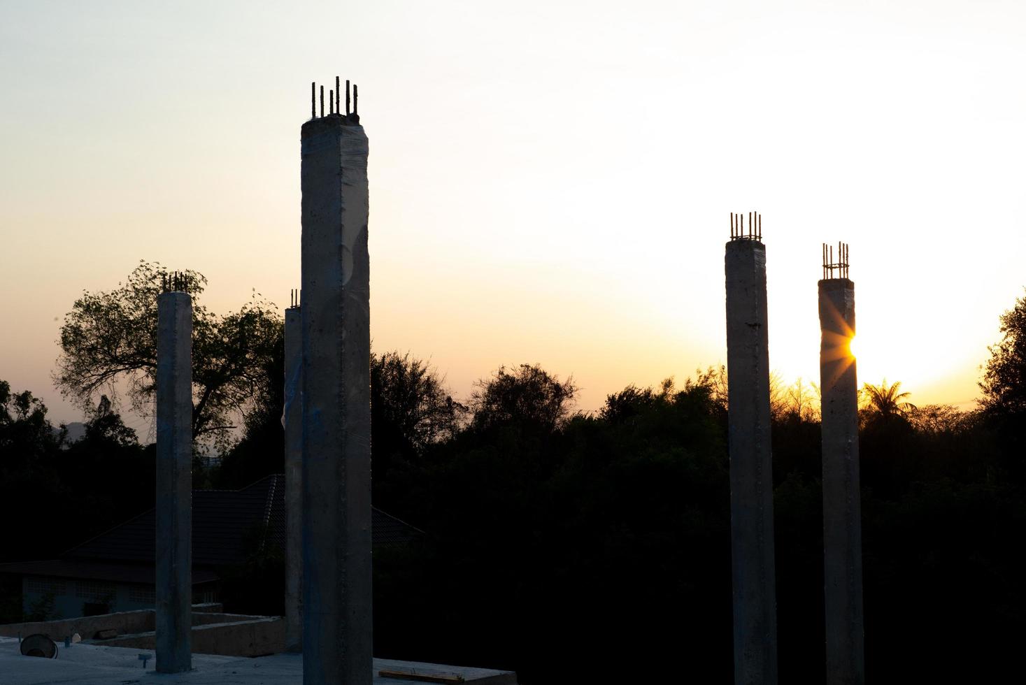 primo piano di colonne di cemento che riflettono la luce del sole in un cantiere edile con uno sfondo blu del cielo foto