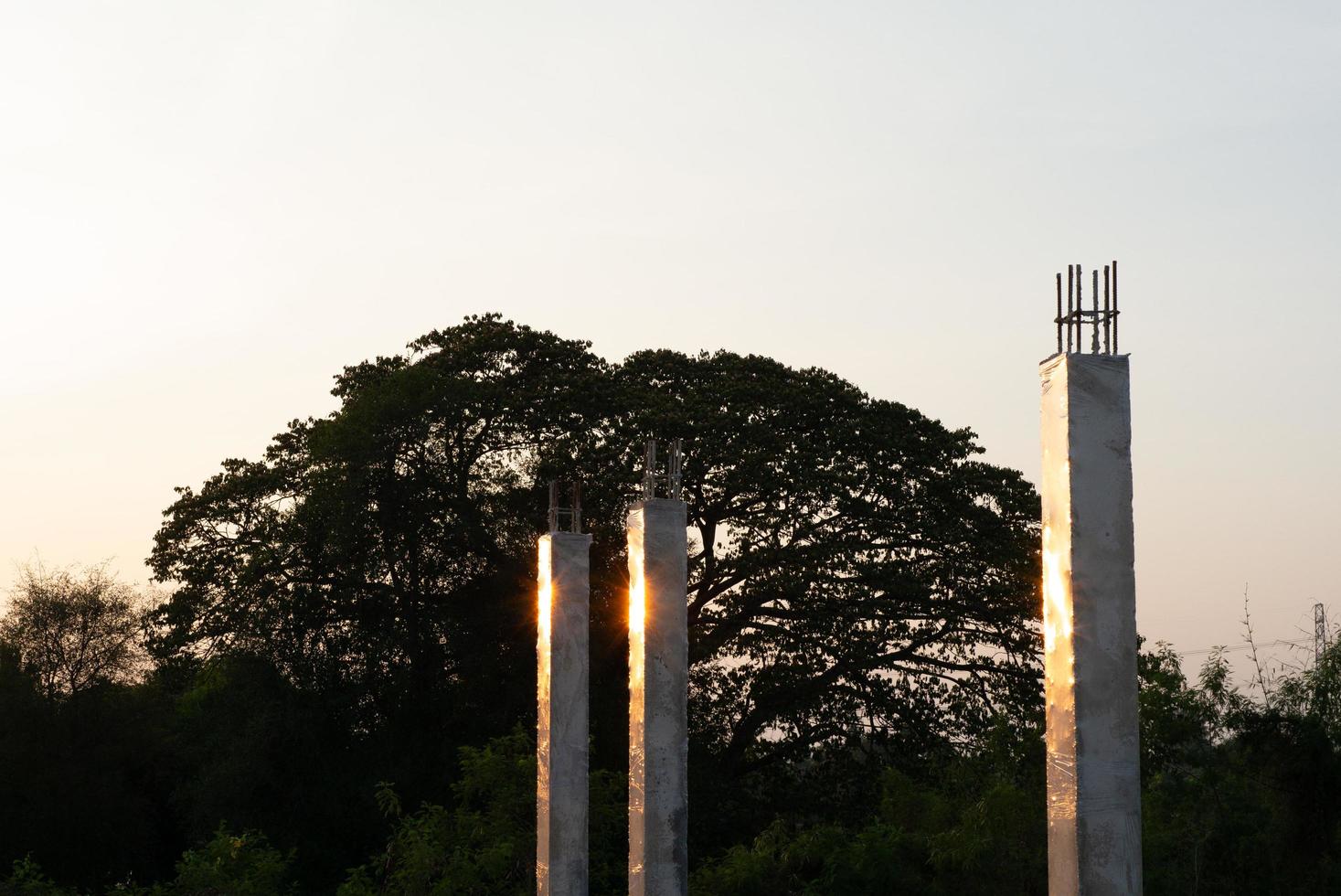 primo piano di colonne di cemento che riflettono la luce del sole in un cantiere edile con uno sfondo blu del cielo foto